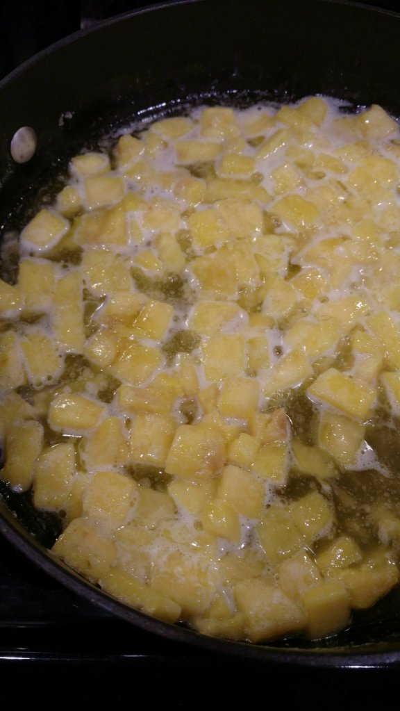 Pineapple cooking in a pan with melted butter. 